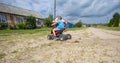 In the rays of the setting sun, a boy rides an ATV. Quad bike. A child rides along the road in a village on an ATV Royalty Free Stock Photo