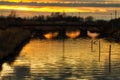 Sunset on river under ancient railway bridge Royalty Free Stock Photo