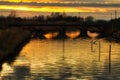 Sunset on river under ancient railway bridge