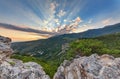 Rays of the sun passing through a cloud above the mountain. The hilly landscape of the valley