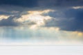 The rays of the sun penetrate the dark clouds over a white snowy field_ Royalty Free Stock Photo