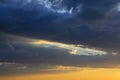 The rays of the sun setting beyond the horizon illuminate the gray clouds, which are located not high above the earth`s surface Royalty Free Stock Photo