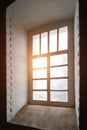 Rays of the sun at sunset make their way through a large old window in a tower with thick stone walls