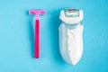 Razor and epilator on blue background. Royalty Free Stock Photo