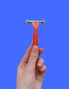 Razor in a female hand on a white background. Removal of unwanted hair. top view. Concept of using razor. Orange men`s razors Royalty Free Stock Photo