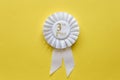 3rd place white ribbon rosette on yellow Royalty Free Stock Photo