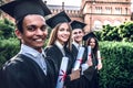 Were educated and ready to go!Happy graduates are standing in university outdoor in mantles with diplomas in hand smiling and