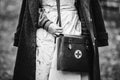 Re-enactor Wears Historical German Nurse Paramedic Of World War II Uniform With First Aid Kit. Photo In Black And White