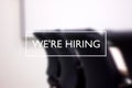 We`re hiring text against blurred meeting room. Recruitment, employment concept