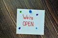 We`re Open write on sticky note and isolated on Wooden Table. Business Concept Royalty Free Stock Photo