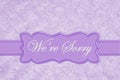 We`re Sorry message on a pale purple rose plush fabric with ribbon