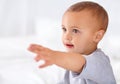 Reaching, cute and boy baby in bed in the nursery of modern family home relaxing and sitting. Smile, arm and sweet happy Royalty Free Stock Photo