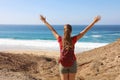 Reaching goal. Female hiker backpacker arrives at the Atlantic Ocean after a long way and celebrating with arms up