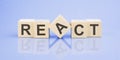 REACT word written on wood block. blue background. business concept. inscription on the cubes is reflected from the surface of the