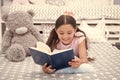 Read fairytale in bed. Girl child lay bed with teddy bear read book. Kid prepare to go to bed. Time for evening Royalty Free Stock Photo