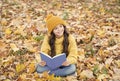 Read readily. Happy child read book sitting on autumn leaves. School library. Literacy education. Literature lesson