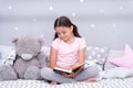 Read before sleep. Girl child sit bed with teddy bear read book. Kid prepare to go to bed. Pleasant time in cozy bedroom Royalty Free Stock Photo