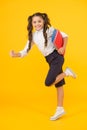 Reader rushing for books. Happy little girl holding books with colorful covers on yellow background. Cute small child Royalty Free Stock Photo