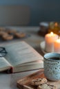 Reading book on cozy winter evening with candles, tea and cookies. Royalty Free Stock Photo