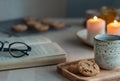 Reading book on cozy winter evening with candles, tea and cookies. Royalty Free Stock Photo