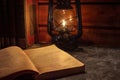 Reading a book in the light of an old hand-held kerosene lamp glows softly in a dark room on the table. Vintage style. Royalty Free Stock Photo