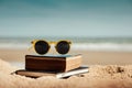 Reading Book Outdoor in Summer Concept. Book and Sunglasses on the Beach Sand in front of the Sea Royalty Free Stock Photo