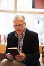 Reading, books and mature man in library for literature, information and knowledge in bookstore. Bookshelf, shopping and Royalty Free Stock Photo