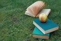 Books on green crap, open book in the background. Apple on books Royalty Free Stock Photo