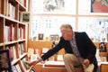 Reading, books and senior man in library for literature, information and knowledge in bookstore. Bookshelf, shopping and Royalty Free Stock Photo