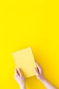 Reading concept. Reading as hobby. New knowledge. Hands take hardback book with empty cover on yellow background top Royalty Free Stock Photo