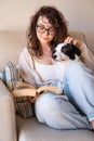 Reading with dog sitting on sofa in sunny light library living room. Royalty Free Stock Photo