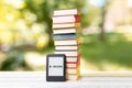 Reading. E-book reader and a stack of books. The park is blurred in the background. Concept of education and electronic gadgets Royalty Free Stock Photo