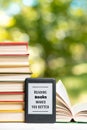 Reading. E-book reader and a stack of books. The park is blurred in the background. Copy space. Vertical. Concept of education and Royalty Free Stock Photo