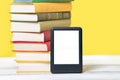 Reading. E-book reader and a stack of books on a yellow background. Mock up. Concept of education and electronic gadgets