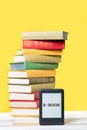 Reading. E-book reader and a stack of books on a yellow background. Vertical. Copy space. Concept of education and electronic Royalty Free Stock Photo
