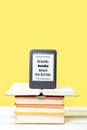 Reading. E-book stands on a stack of books on a yellow background. Copy space. Vertical. Concept of education and electronic Royalty Free Stock Photo