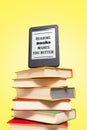 Reading. E-book on top of a stack of books on a yellow background. Vertical. Concept of education and electronic gadgets Royalty Free Stock Photo