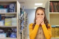 Scared student girl closing mouth at library Royalty Free Stock Photo