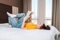 Reading and education. A young woman reads a magazine lying on the bed. Home interior. Side view Royalty Free Stock Photo