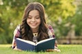 Reading only enhances your knowledge. Happy child read book lying on green grass. School library. Imagination and