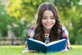 Reading only enhances your knowledge. Happy child read book lying on green grass. School library. Imagination and