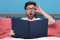 Surprised young man in glasses readingthe book at home Royalty Free Stock Photo