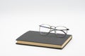 Reading glasses on black book isolated on white background Royalty Free Stock Photo