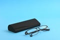 Reading glasses and black hard case isolated on blue background Royalty Free Stock Photo