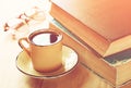 Reading glasses, stack of old books and smartphone over wooden table, retro filtered image