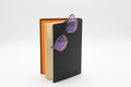 Reading glasses on Standing black book with orange inlay isolated on a white background Royalty Free Stock Photo