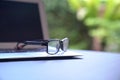 Reading glasses on top of computer laptop. Green nature background Royalty Free Stock Photo