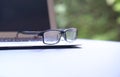 Reading glasses on top of computer laptop. Green nature background Royalty Free Stock Photo