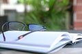 Reading glasses on top of an open book. Garden or green nature background Royalty Free Stock Photo