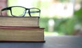 Reading glasses on top of stack of books. Garden or green nature background Royalty Free Stock Photo